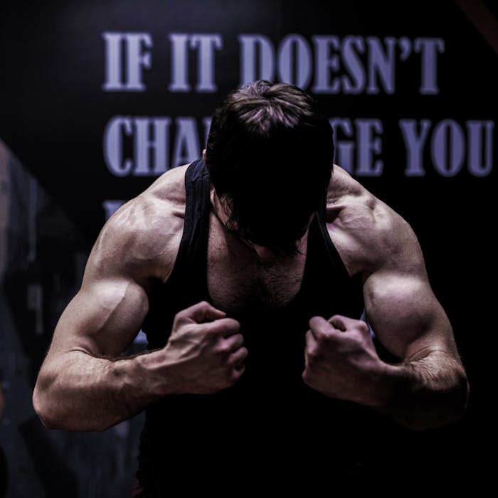 hero-img-01 Muscular male bodybuilder posing in a dimly lit gym, showcasing strength and dedication.